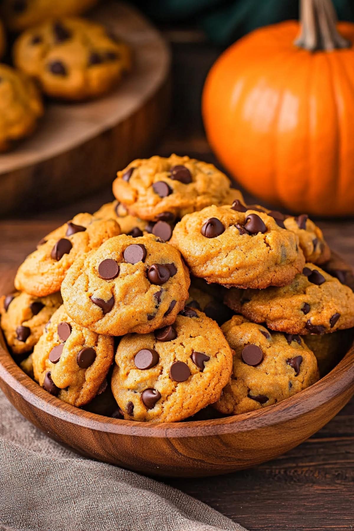 A wooden bowl filled with pumpkin chocolate chip cookies.