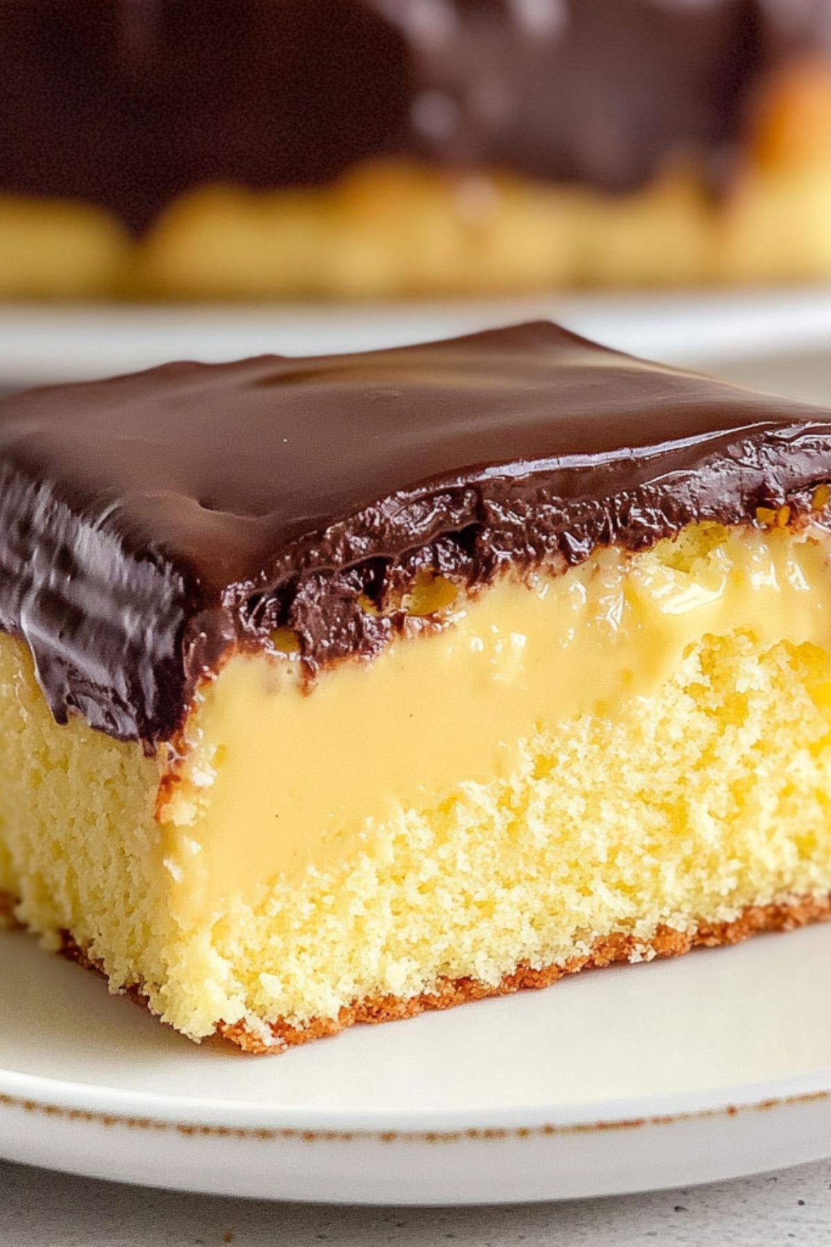 Slice of moist Boston cream pie poke cake served in a white plate, close up