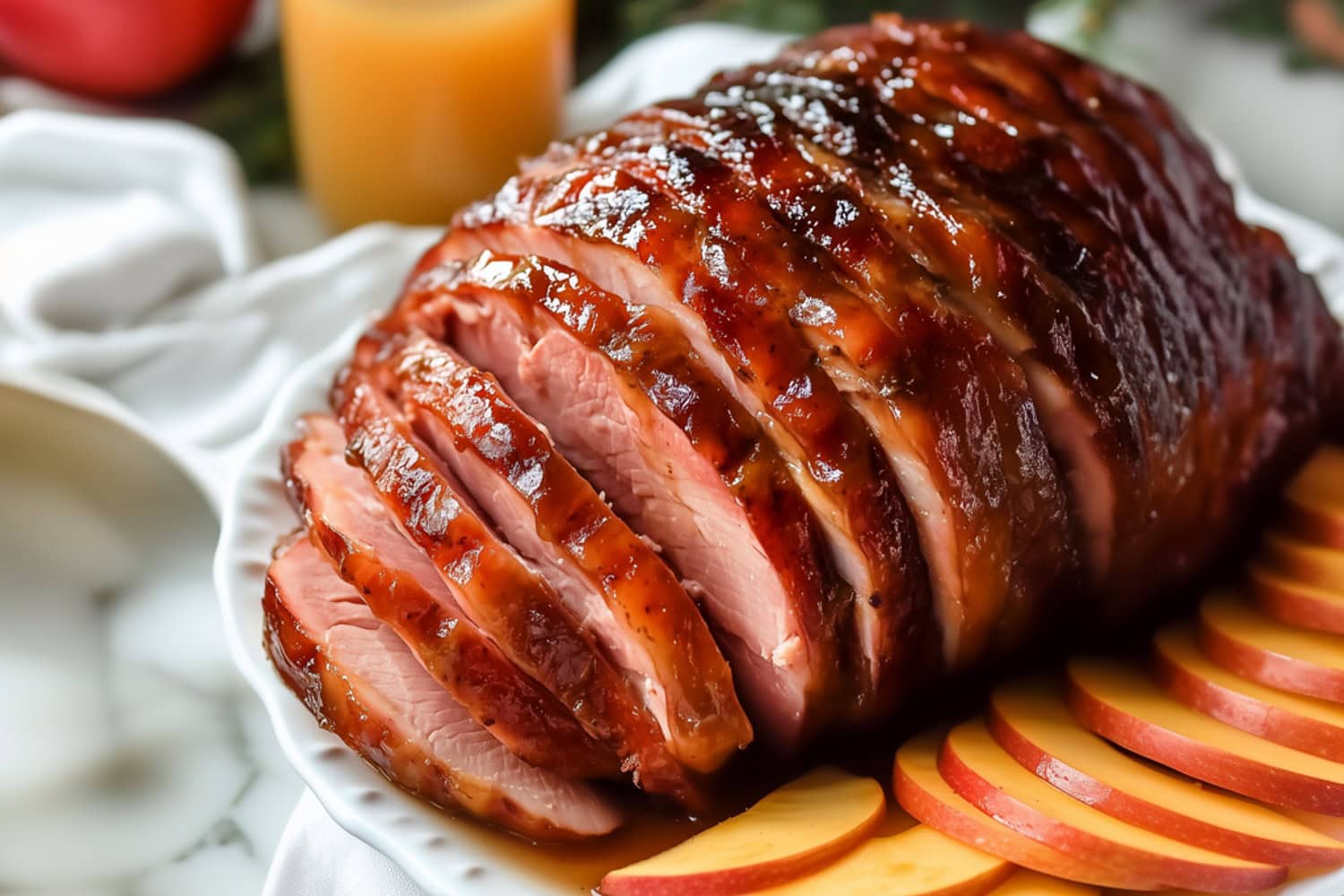 A perfectly roasted ham with a sweet maple glaze served in a white plate.