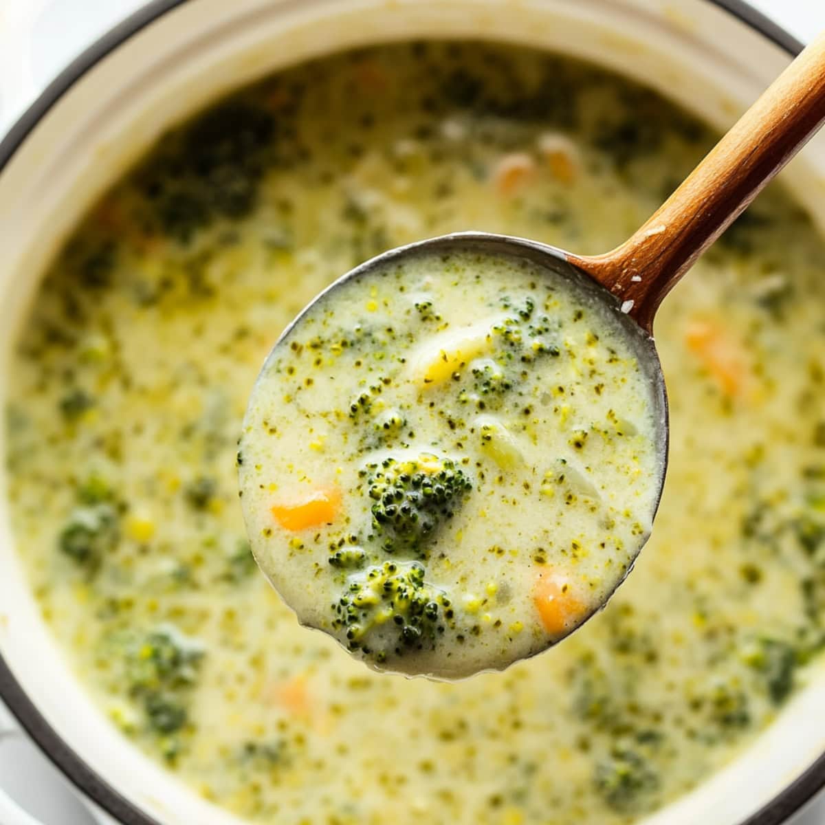 Broccoli cheddar soup in a pot, serving lifted by a ladle. 