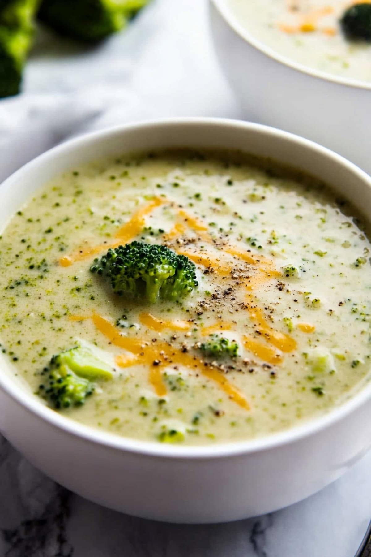 Broccoli cheddar soup in a bowl garnished with grated cheddar cheese.