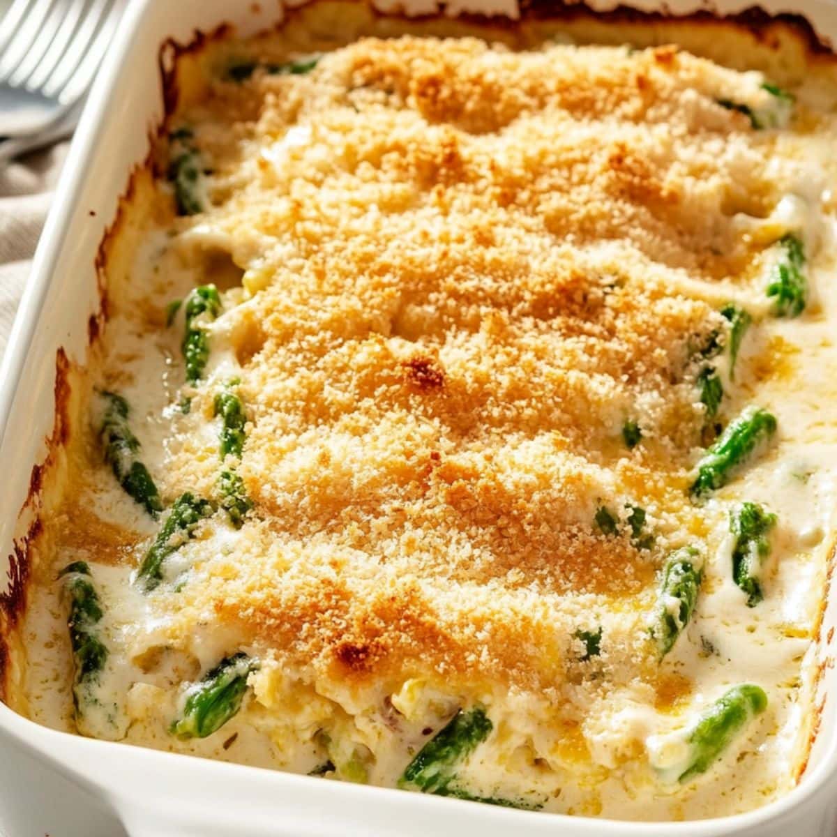 Cheesy asparagus casserole in a baking dish topped with Panko breadcrumbs.