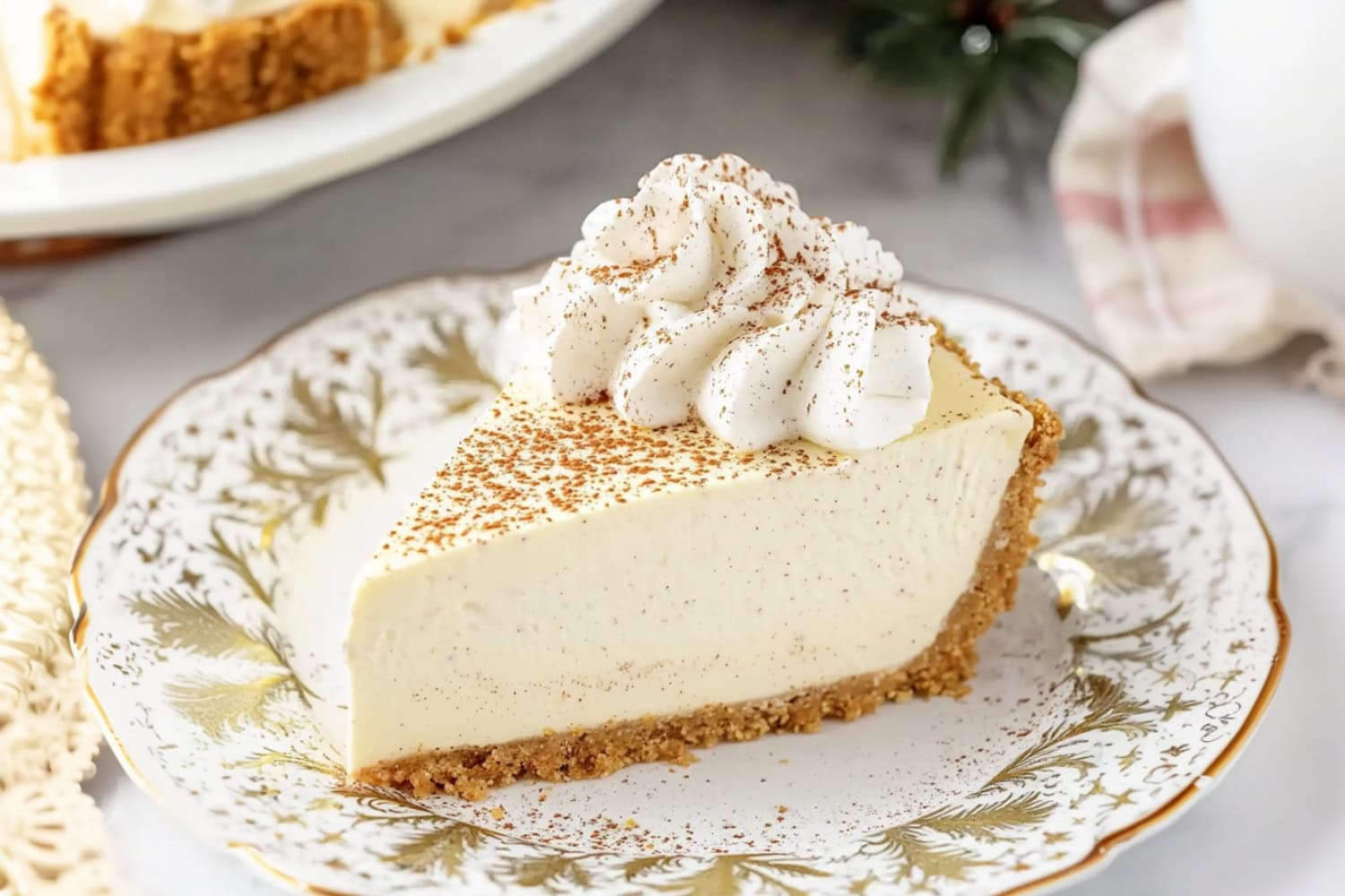 A slice of eggnog cheesecake, showing a smooth, creamy filling infused with holiday spices, topped with whipped cream and served on a crunchy graham cracker crust.